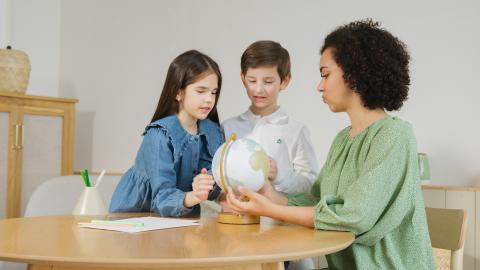 Parent teaching children with globe